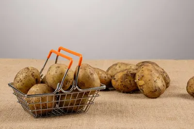 Aardappelen in een metalen mandje en los op een jute ondergrond