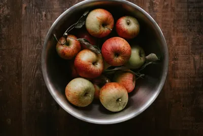 Kleine rode appels in een metalen schaal op een donkere houten tafel