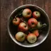 Kleine rode appels in een metalen schaal op een donkere houten tafel