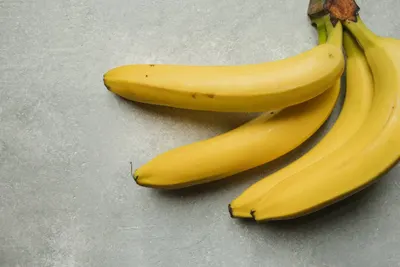 Een tros gele bananen op een grijze ondergrond