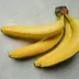 Een tros gele bananen op een grijze ondergrond