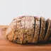 Een half gesneden donker brood op een houten plank