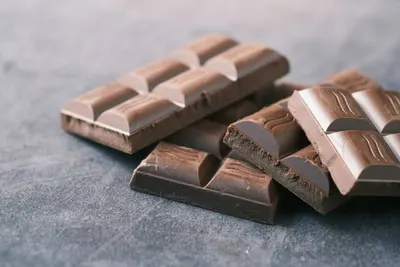 Gebroken stukken melkchocolade op een grijze ondergrond
