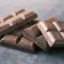 Gebroken stukken melkchocolade op een grijze ondergrond