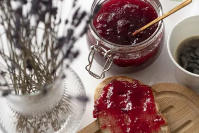 Een pot rode jam en een boterham met jam