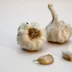 Twee knoflookbollen en losse teentjes op een witte ondergrond