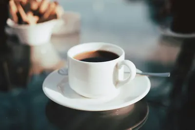 Een wit kopje zwarte koffie op een schoteltje
