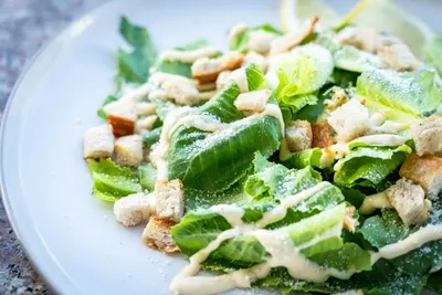 Een bord Caesarsalade met romaine sla, croutons en dressing