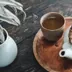 Een witte theepot en een kopje thee op een houten dienblad