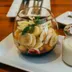 Een glas met yoghurt en banaan naast een potje yoghurt