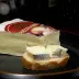 Een punt brie en een sneetje brood met brie op een donker bord