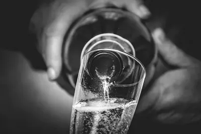 Zwart-witfoto van prosecco die in een glas wordt geschonken