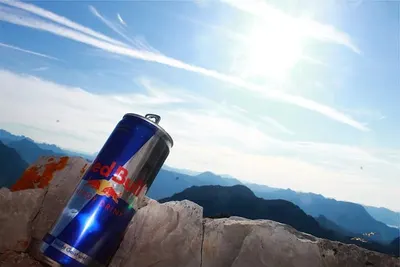 Een blikje energiedrank op een rots in de bergen onder een blauwe lucht
