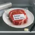 Rauwe biefstuk in vacuümverpakking met label ‘Portie 250 g’ in de koelkast naast een koelkastthermometer