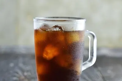 Een glas ijskoffie met ijsblokjes en koffiebonen