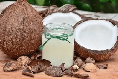 Kokoswater in een glazen potje tussen hele en gehalveerde kokosnoten