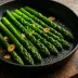 Gebakken groene asperges met knoflook in een zwarte pan