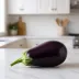 Een hele aubergine op een wit keukenaanrecht