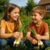 Twee lachende kinderen in de moestuin met een bosje lente-uitjes in hun handen