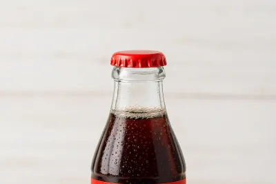 Een glazen flesje Coca-Cola op een witte ondergrond
