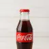 Een glazen flesje Coca-Cola op een witte ondergrond