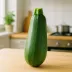 Eén hele courgette rechtop op een houten aanrecht