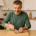 Een man snijdt plakjes droge worst op een houten plank