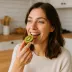 Een vrouw neemt een hap van een halve kiwi