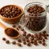 Koffiebonen in een glazen pot en houten schaal met een lepel gemalen koffie