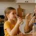 Een moeder en dochter drinken water uit glazen flesjes in de keuken