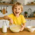 Een jongen klopt pannenkoekenbeslag in een kom in de keuken