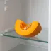 Een partje oranje pompoen met pitten op een koelkastplank
