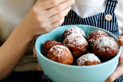 Een moeder en kind met een schaal oliebollen met poedersuiker
