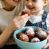 Een moeder en kind met een schaal oliebollen met poedersuiker